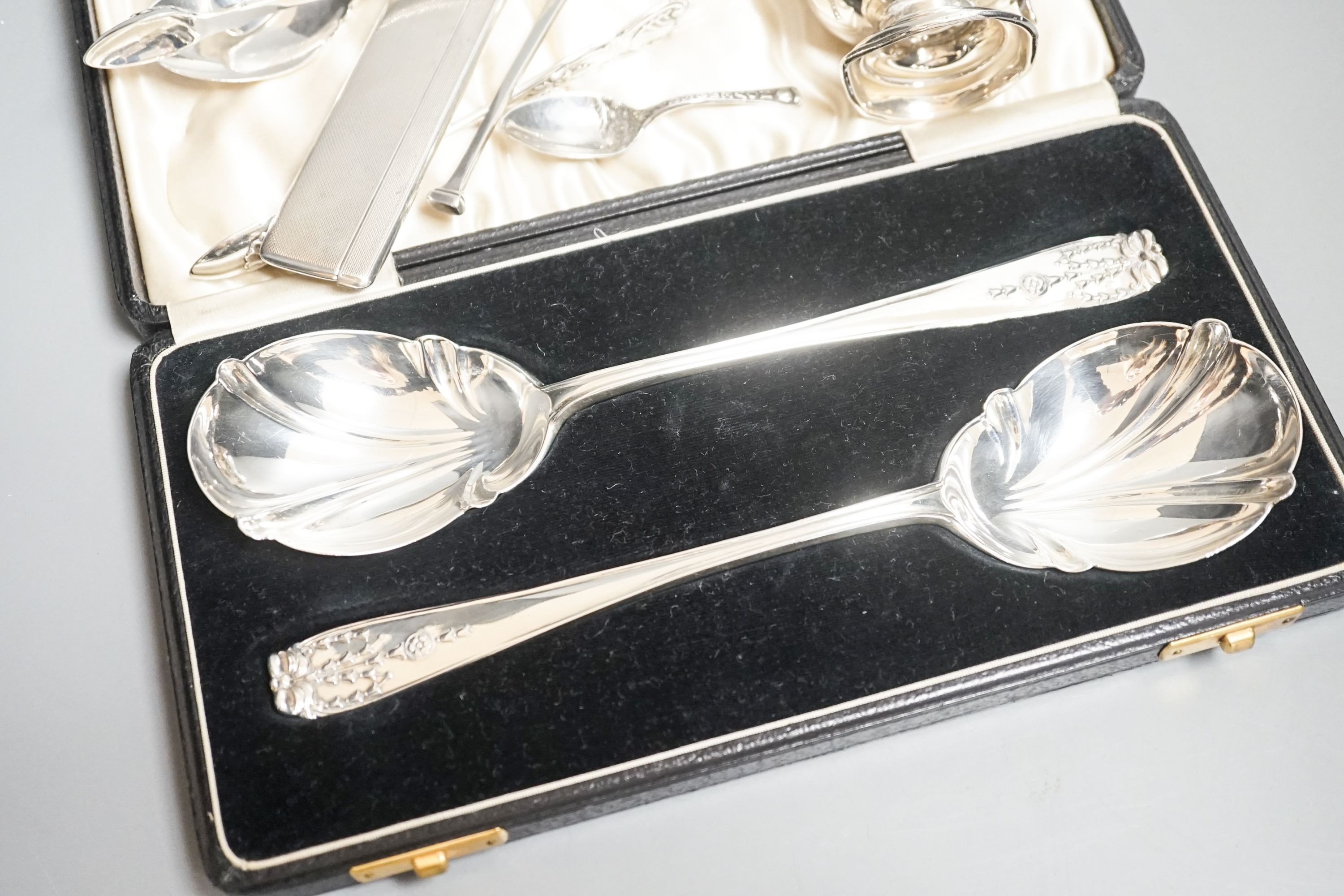 A cased pair of silver serving spoons, a silver christening mug and minor silver flatware, comb, etc.